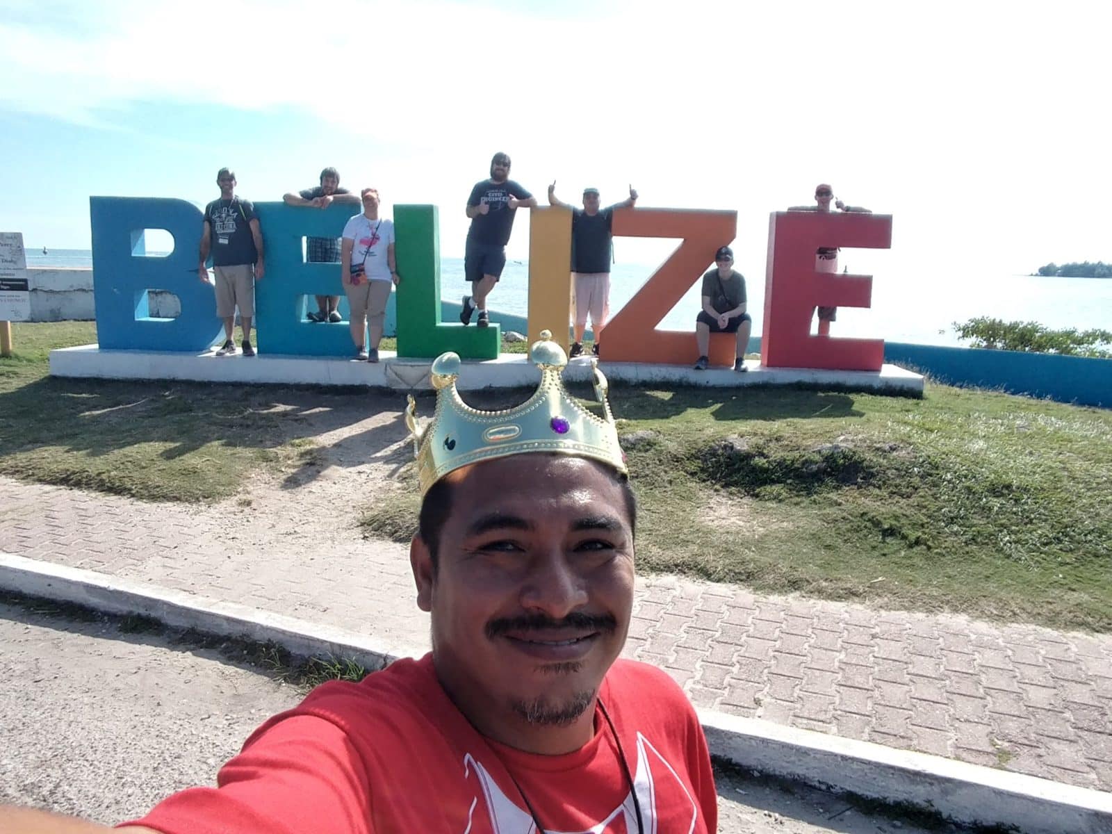 Tour Guide King David poses for selfie with family at Belize sign.