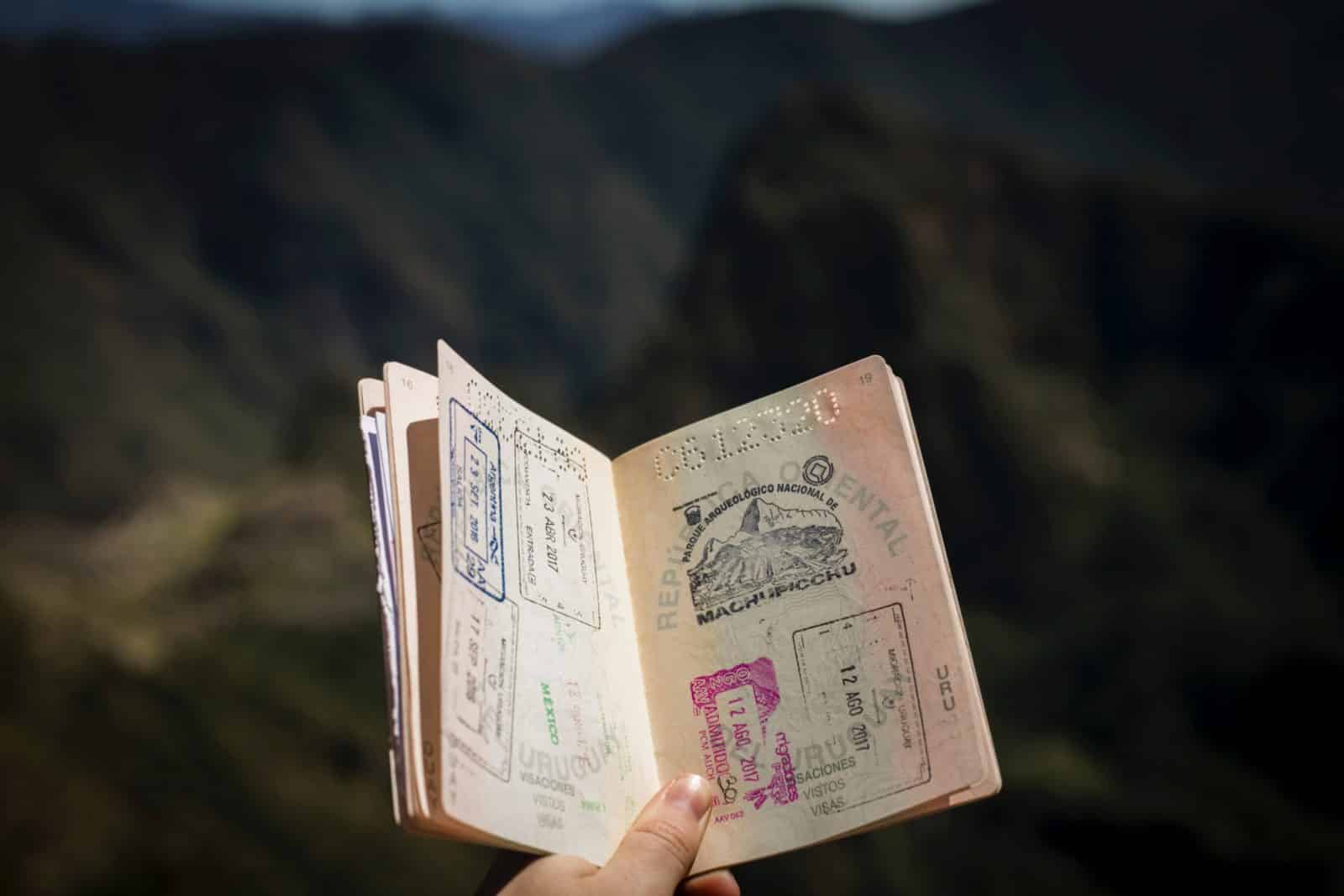 a passport with stamps in someones hand is held open.