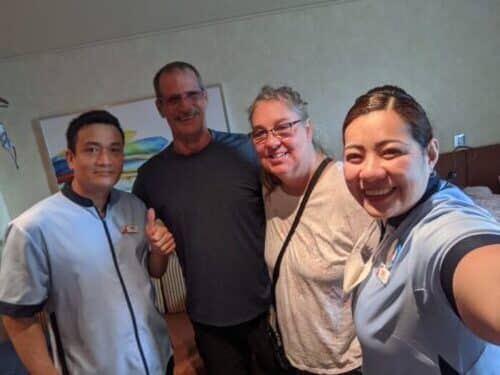 Couple pose with room steward Shelia and assistant on Carnival Panorama