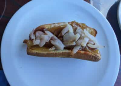 Hot Dog and onions on a white place from Carnival Deli