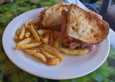 golden french fries on a white plate with a toasted Reuben sandwich