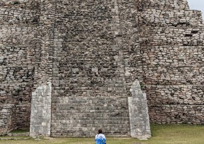 woman in a blue shirt sits on rocks gazing at a huge Mayan ruin near Yucatan, MX. Gallivanting Souls visited Progresso on Carnival Valor.