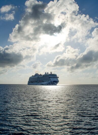 cruise ship sailing into a sun and cloud filled horizon