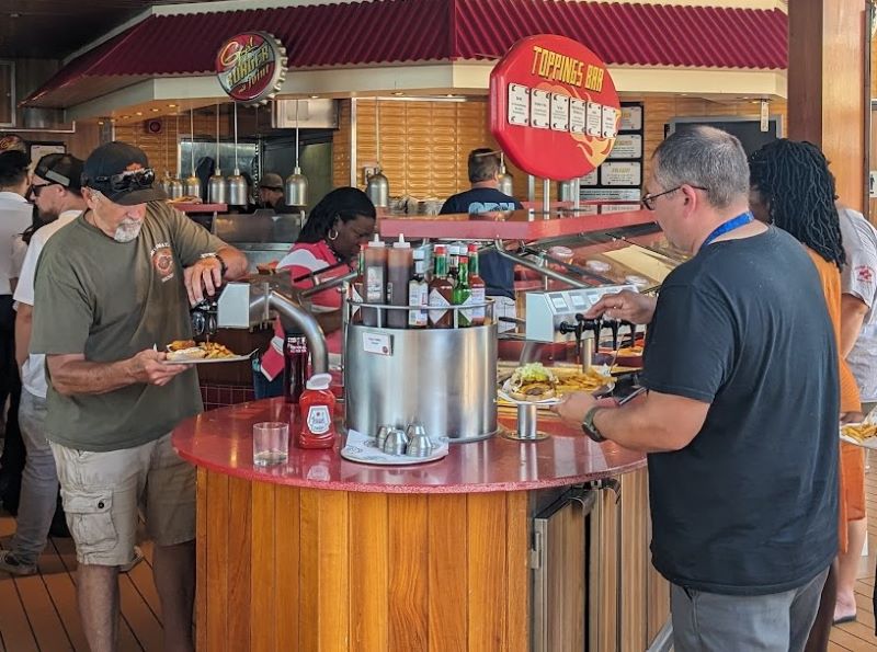 Hungry passengers gather round the toppings bar at Guy's Burger to customize their burger.