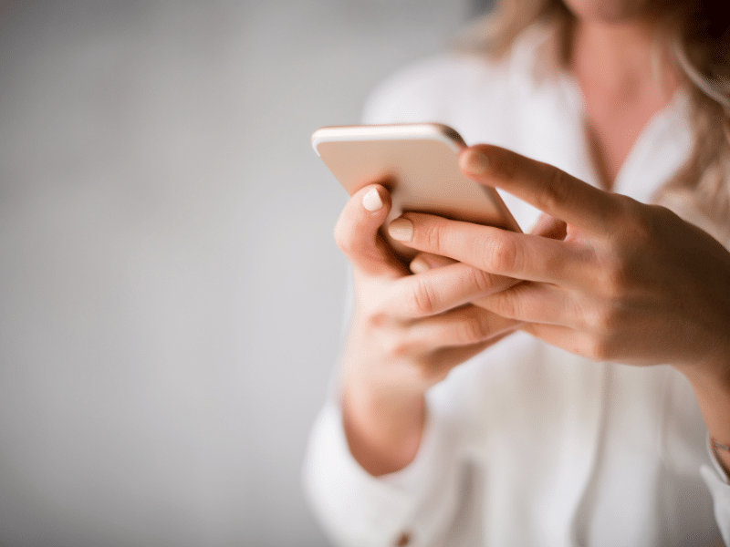 Woman in white sweater holds cellphone
