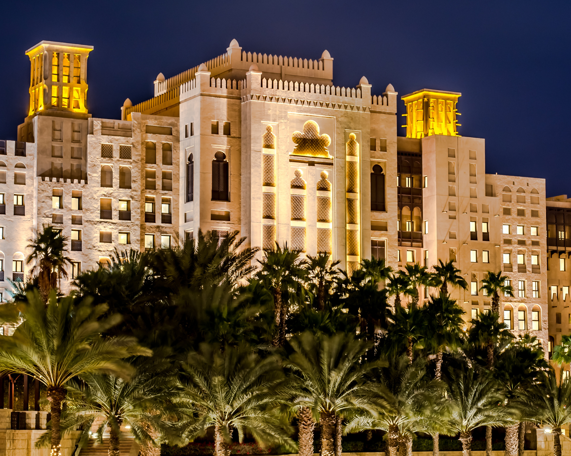 By flying in a day before, you can enjoy A beautiful hotel is lit up at night making for a relaxing evening before getting on ship.