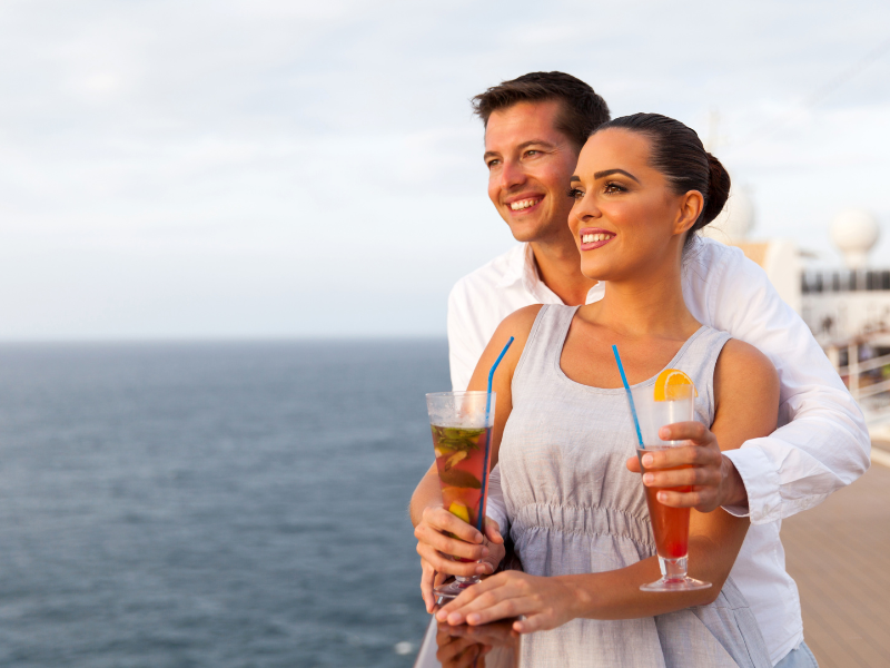 couple with drink package look out to sea toasting their happiness