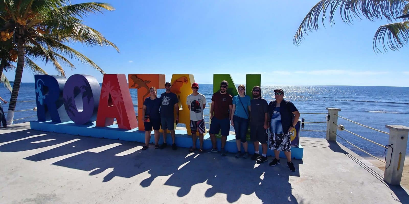Group stands in front of Roatan sign adventures monkeys sloths snorkeling