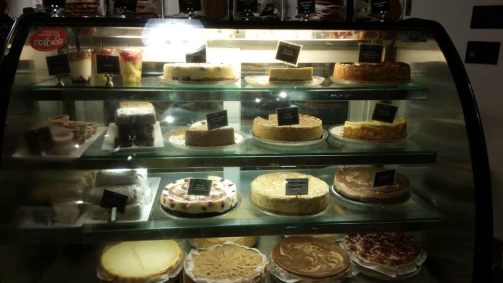 Many flavors of cheesecake in a cold case display